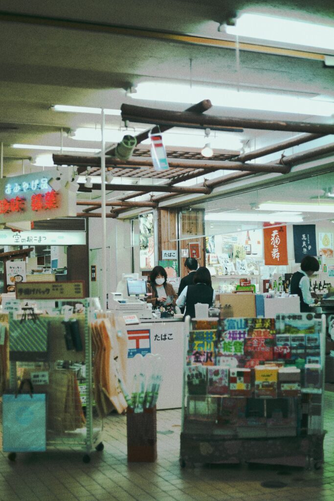 In a Japanese grocery store, people check out with their items. People are grocery shopping in a Japanese store.